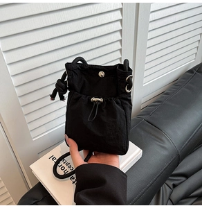 Close-up of black nylon crossbody bucket bag with drawstring and metal snap button