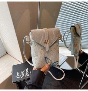 Détail du sac en toile brodé avec boucle en cœur et vue latérale par reflet