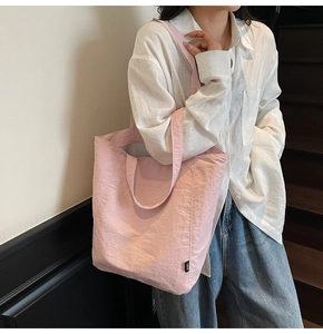 Detail of pink lightweight nylon tote bag featuring durable straps and soft pleated texture