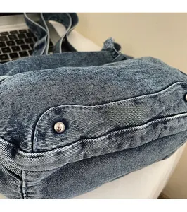 Close-up of blue denim tote bag with silver metal rivets and durable stitching details