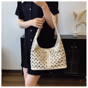 Close-up of cream leather hobo bag with silver punk rivets and metallic eyelets details