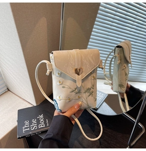 Détail de la broderie de marguerites et de la boucle cœur sur le sac en toile blanc cassé