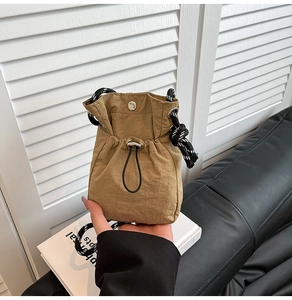 Detail of khaki drawstring mini bucket bag with adjustable textured woven shoulder strap