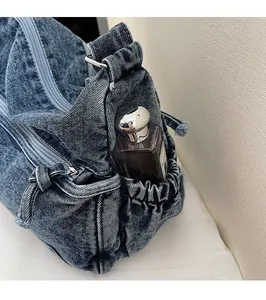 Detail view of denim tote bag side pocket with drawstring and perfume for scale