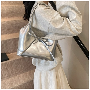 Detailed view of a silver metallic PU shoulder bag featuring a large bow on the strap
