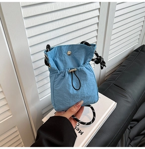 Detail of sky blue drawstring mini crossbody bag with woven strap and silver metal buckle