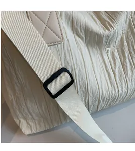 Detail view of cream canvas tote showing adjustable nylon strap and crinkled fabric texture