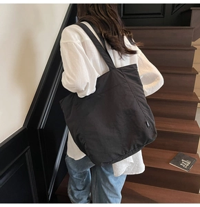 Close-up of a large black tote bag with wide straps for casual daily commuting