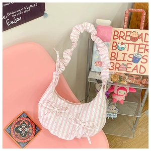 Detail of pink and white striped dumpling bag featuring bow accents and ruffled strap