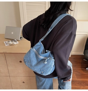 Detail of blue denim crossbody bag with vintage washed finish and adjustable strap