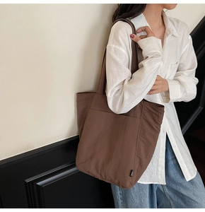 Detail of dark brown tote bag on model showing large capacity and minimalist fabric texture