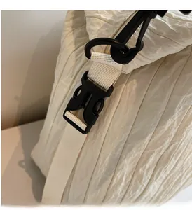 Close-up of durable black plastic buckles and quilted texture on cream canvas bag