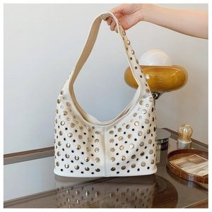 Detail of white leather hobo bag with silver metal studs and hollow ring patterns