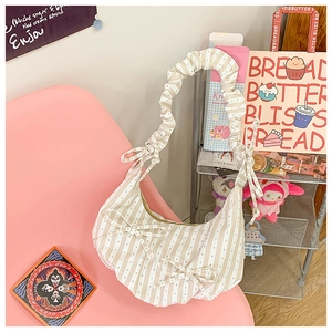 Detail of striped hobo bag with ruched shoulder strap and decorative bows in cream
