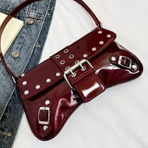 Dettaglio borsa a spalla in pelle verniciata bordeaux con borchie e fibbie in metallo argento