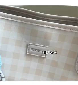 Detailed close-up of the beige checkered pattern and leather logo patch on the tote bag