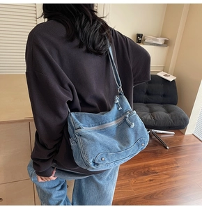 Modern washed blue denim tote bag with metal rivets shown in a casual lifestyle setting