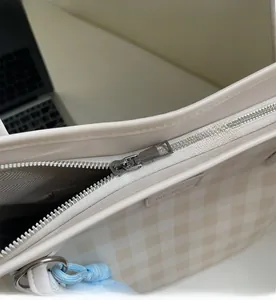 Detail view of the smooth metal zipper closure on the gingham check tote bag
