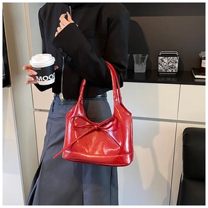 Detail shot of the bright red bow and glossy PU leather surface of this tote bag
