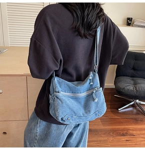 Blue denim crossbody bag featuring multiple zipper pockets and adjustable strap shown on model