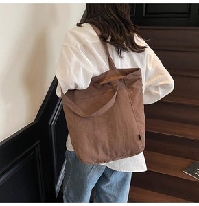 Lifestyle shot of woman carrying large brown tote bag on stairs showing shoulder strap detail