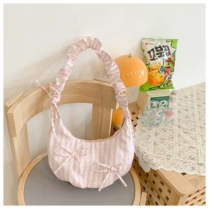 Detail of pink striped shoulder bag with bows and ruffle strap on a wooden chair