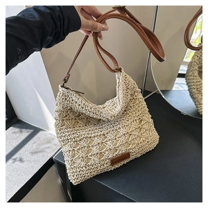 Close-up of cream woven shoulder bag with brown faux leather strap and zipper detail
