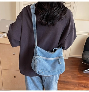 Blue denim crossbody tote bag shown from the back with adjustable strap and metal hardware