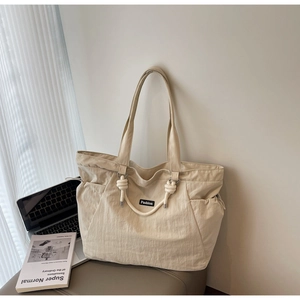 Détail du sac fourre-tout en nylon beige avec poignée à nœud et étiquette de mode
