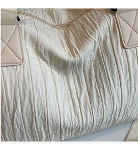 Detail of the soft pleated fabric and sturdy stitching on the beige canvas tote bag