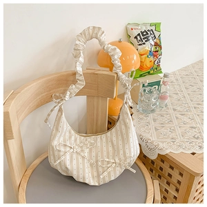Detail of a beige striped dumpling bag with bow accent and pleated strap on a wooden chair