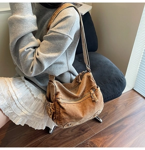 Close-up of brown canvas tote bag with multi-layer zippers and adjustable wide strap