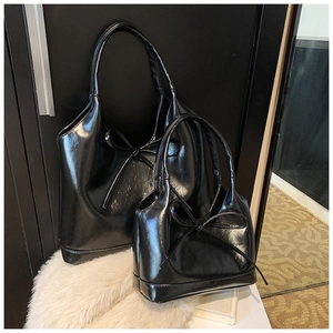 Detail of black glossy PU leather tote bag with elegant ribbon bow and inner pouch