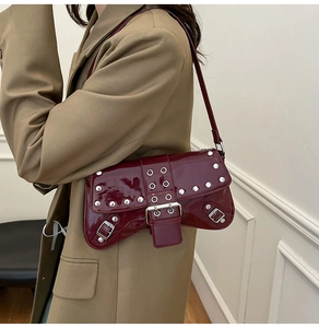 Detalle del bolso de hombro en charol rojo oscuro con remaches y hebillas plata