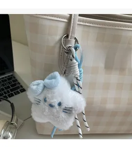 Close-up of star plush charm with blue bow and woven lanyard on a beige tote bag