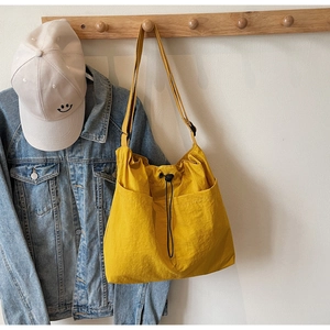 Detail of yellow nylon bucket bag with drawstring closure and large front pockets