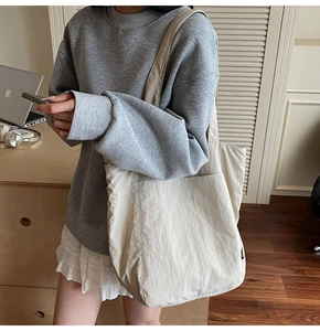 Detailed side view of cream white nylon tote bag showing spacious main compartment and pockets