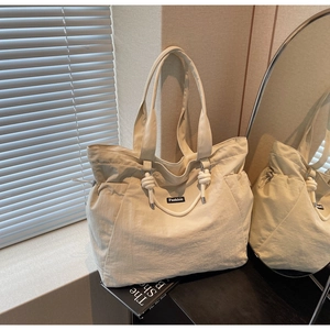 Détail de la poignée nouée et de la texture du nylon beige d'un grand sac cabas