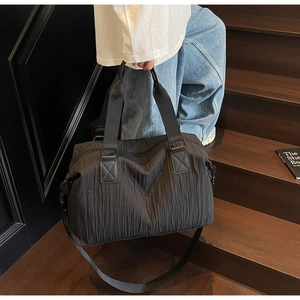 Close-up of black waterproof canvas tote featuring vertical pleated texture and wide handle