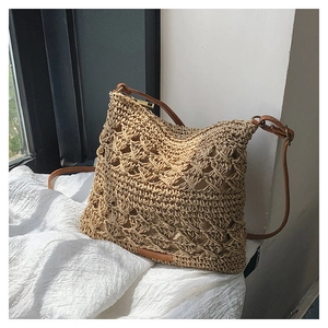 Detail of bohemian straw woven crossbody bag featuring hollow out crochet and leather strap