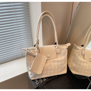 Detail of cream plaid tote bag featuring character embroidery and a small coin purse