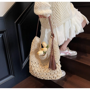 Détail du sac de plage tressé avec breloque à pompon marron et fine bandoulière en cuir souple
