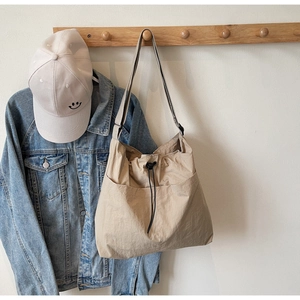 Detail view of khaki nylon bucket bag with dual drawstring pockets and long strap