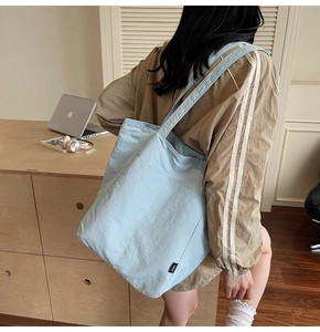 Close-up of light blue nylon tote bag showing textured waterproof fabric and side tag