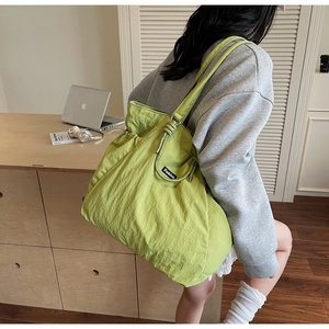 Détail du sac cabas en nylon vert avocat avec nœuds de serrage et étiquette fashion