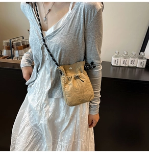 Detail of light khaki drawstring bucket bag with black and white woven shoulder strap