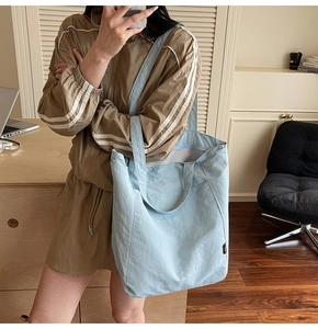 Detailed side view of a large light blue tote bag with a notebook in a modern office