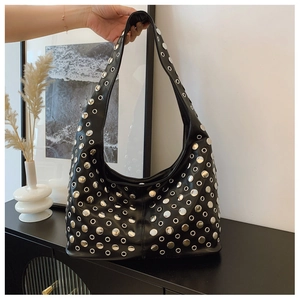 Detail of a black hobo bag with silver metallic rivets and eyelets in a minimalist setting