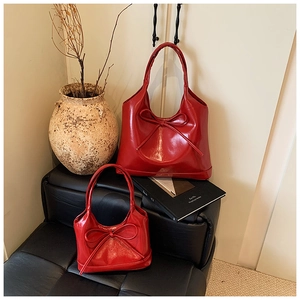 Detail of red PU leather tote bags featuring shiny finish and decorative bow accents