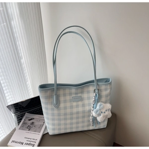 Detail of light blue checkered tote bag with plush cat charm and striped silk scarf decoration